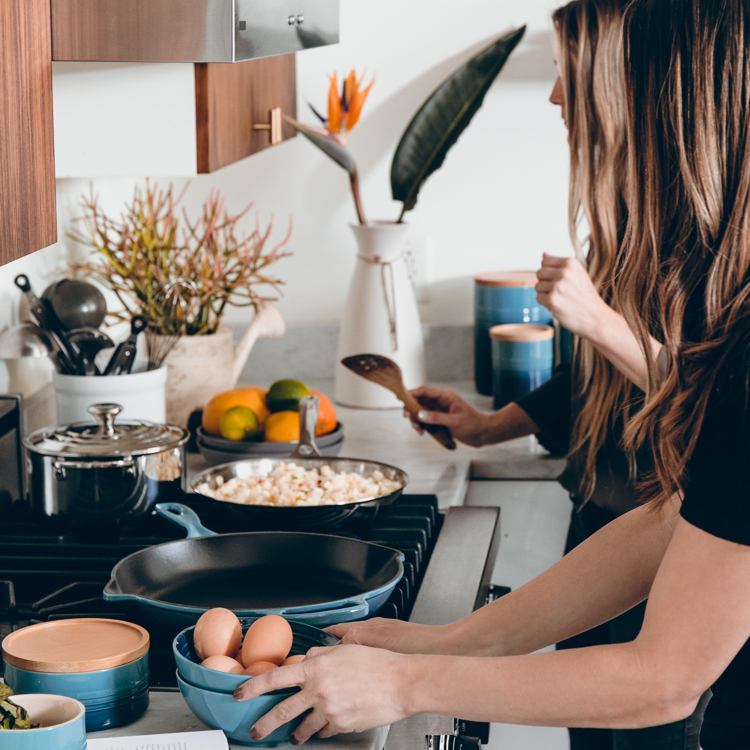 Two women cooking eggs on frying pan